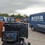 Filming on Location, a carpark full on a companies vans with a camera in the foreground