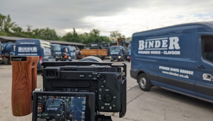 Filming on Location, a carpark full on a companies vans with a camera in the foreground