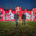 Warehouse Digital Directors, Pete and James standing in front of Hestercombe House. A Large stately home with the Warehouse Digital logo projected all over it at night.